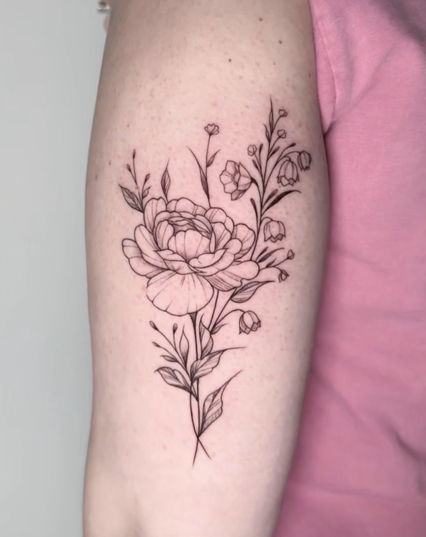 Fine line bloem tattoo op bovenarm